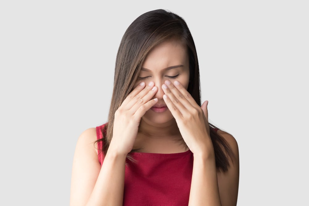 Woman holding nose due to sinus pain