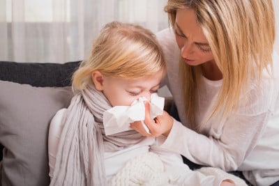 Young mother helping her sick daughter blow her nose